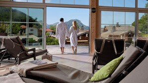A couple walking on a balcony with a mountain view. - Panoramahotel Oberjoch (Bad Hindelang)