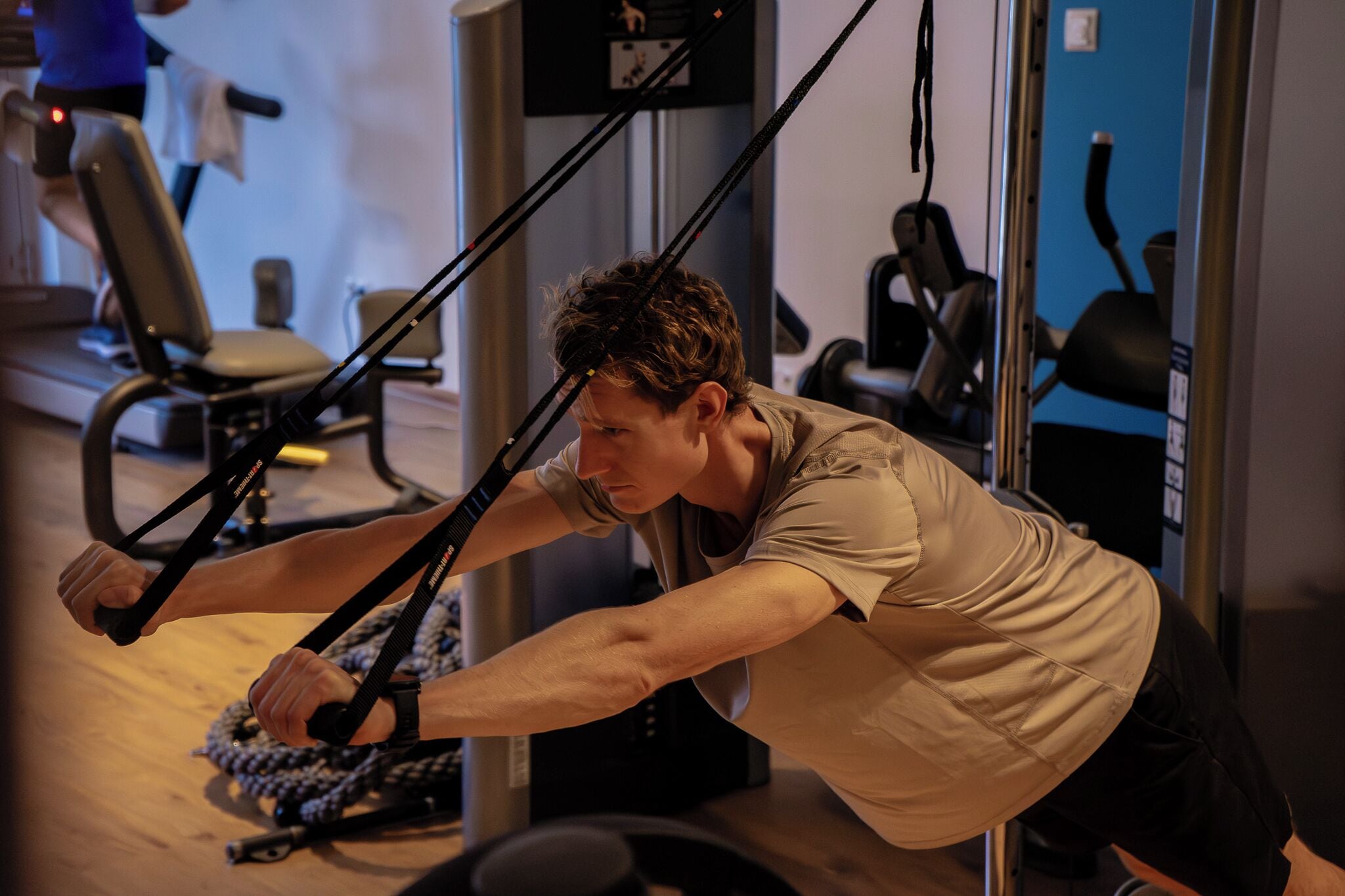 A person using a resistance band exercise machine in a gym.