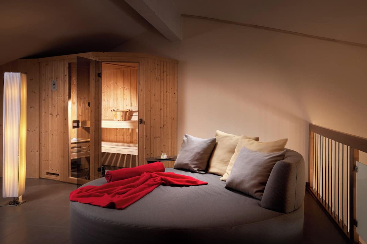 Een gezellig slaapkamer met een bed, kussens, een rode deken, een houten garderobe en een nachtkastje.
