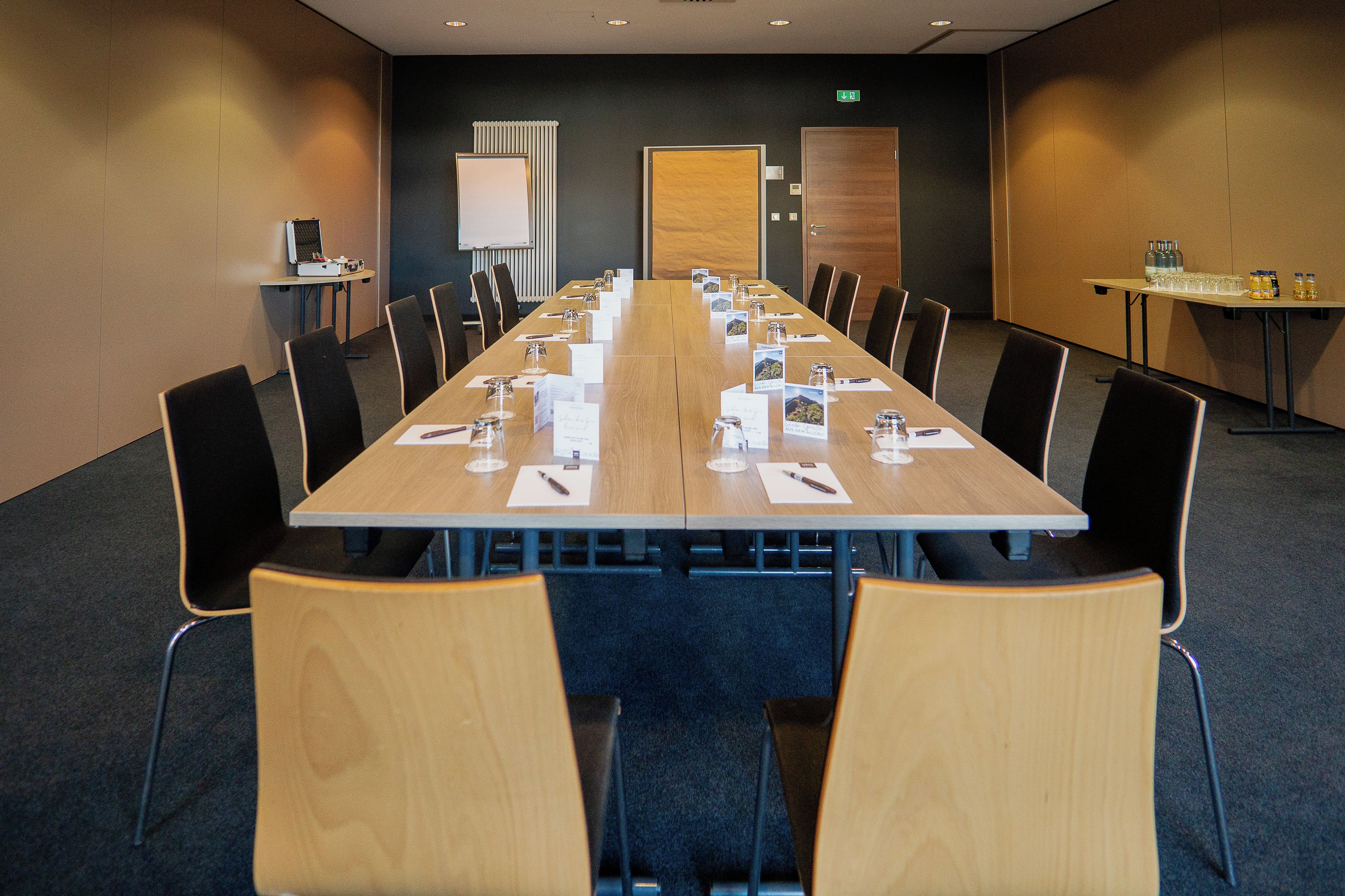 A conference room with a long table, chairs, and a whiteboard.