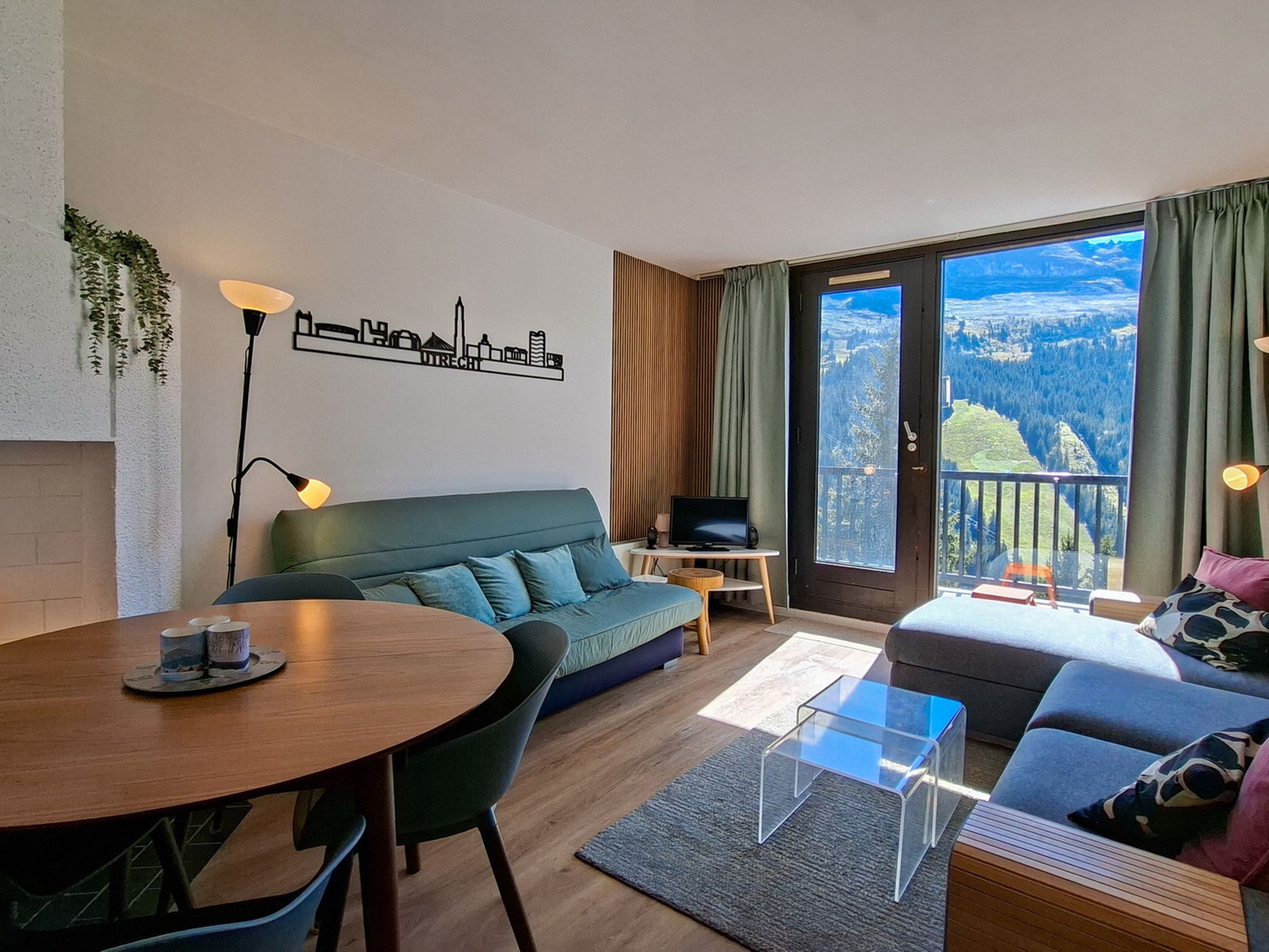 Un salon moderne comprenant un canapé, une table à manger et un téléviseur. Il y a un balcon avec vue sur l’extérieur.