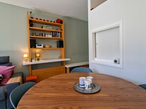 Una habitación acogedora con una mesa de comedor de madera, una estantería y una puerta blanca.