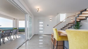 Un intérieur moderne avec un escalier, un balcon doté d’une table et de chaises, et une vue sur l’extérieur.