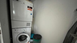 Ett kompakt utrymme för tvätt, med staplade tvättmaskiner och torktumlare, samt en sopbehållare.