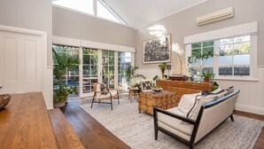 Un salón amplio con un gran ventanal, una mesa de centro de madera, un sofá y varias plantas.
