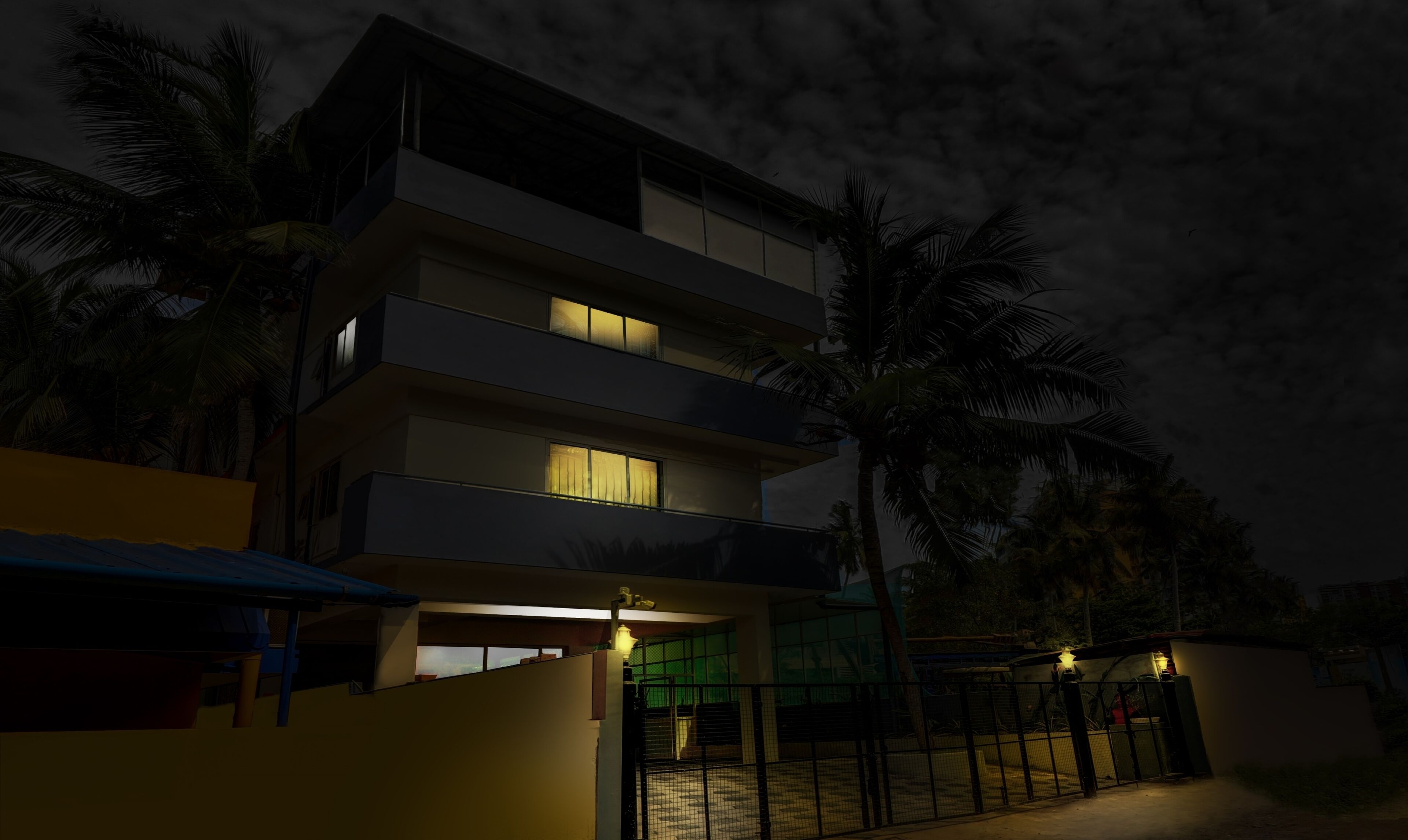 A multi-story building with balconies, a gated entrance, and palm trees.