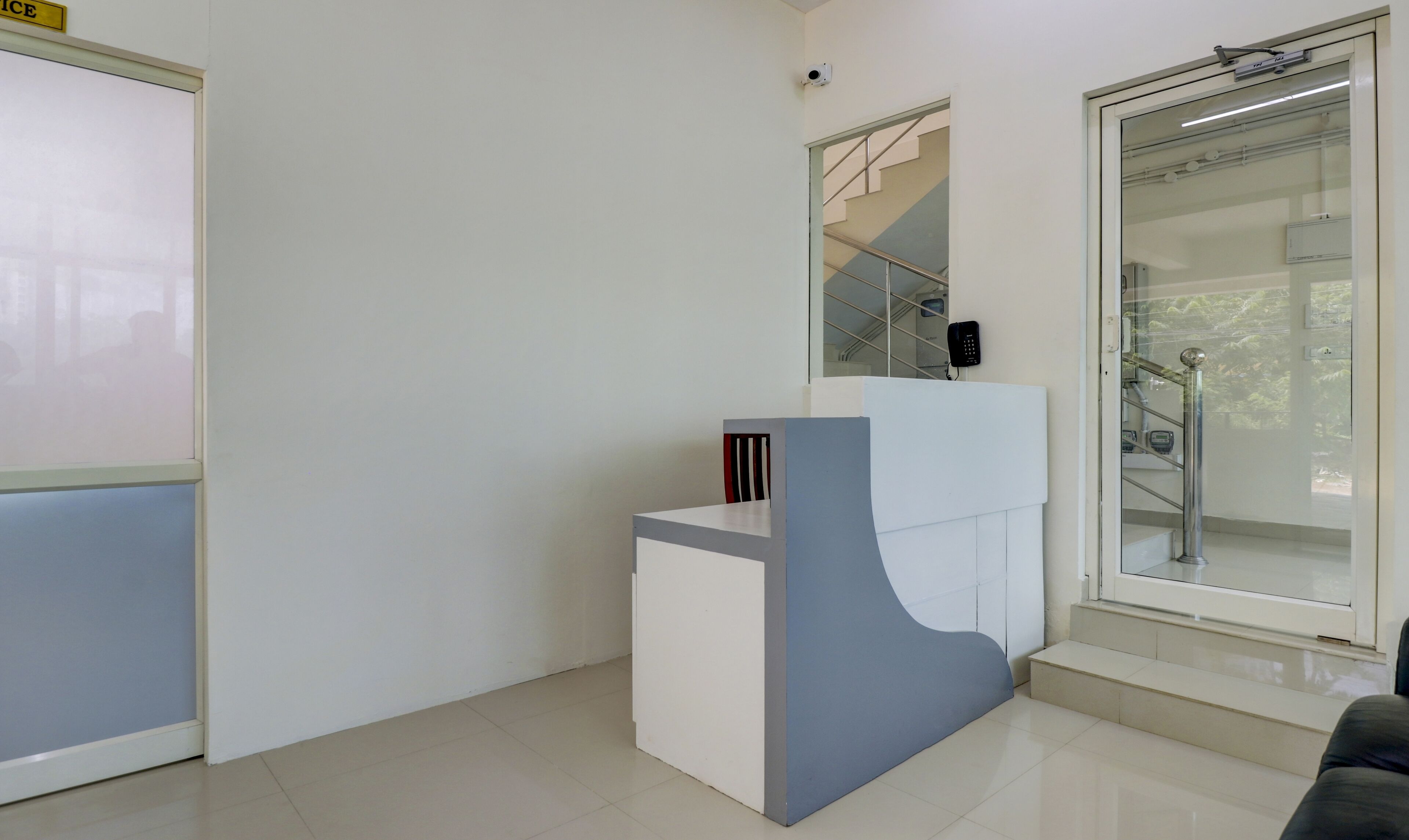 Un espace d’accueil comprenant un comptoir, un téléphone et un escalier menant à l’étage supérieur.