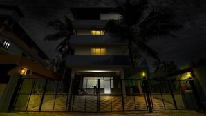 A multi-story building with a gated entrance, palm trees, and a motorcycle parked outside. - Itsy Hotels Ushodaya Royal Residency (Thiruvananthapuram)