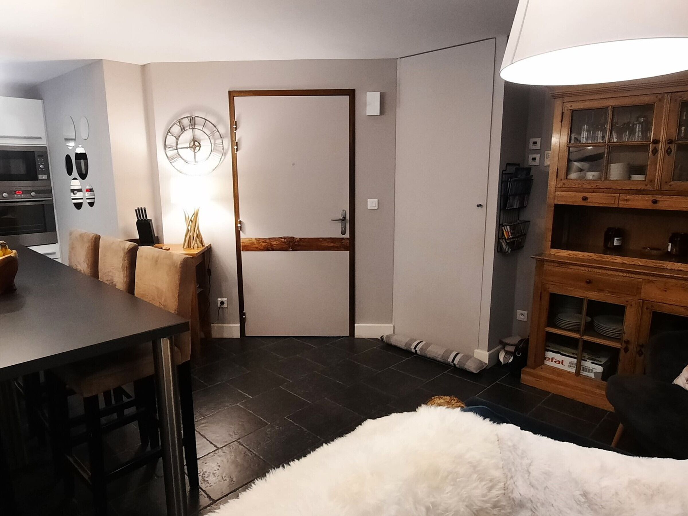 Eine kompakte Küche mit Essbereich, einem weißen, flauschigen Teppich und einem Holzschrank mit Glastüren.
