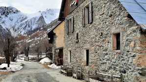 A stone building with a wooden balcony, a snow-covered mountain in the background, and a clear sky. - Comfort 2-room, 6 ppl, Terrace & Garden in Valloire (Valloire)