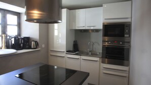 A modern kitchen with a built-in stove, stainless steel appliances, and white cabinetry. - Comfort 2-room, 6 ppl, Terrace & Garden in Valloire (Valloire)