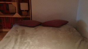 A bed with a beige blanket and two red pillows. - Studio cabin + mezzanine for 4, West-facing balcony in Valloire (Valloire)