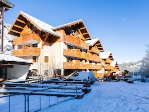 Un edificio cubierto de nieve con varios balcones y un estacionamiento.