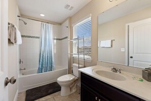 A bathroom with a bathtub, toilet, and sink. - The Cinehaven at Solterra by Shine Villas 407 (Davenport)