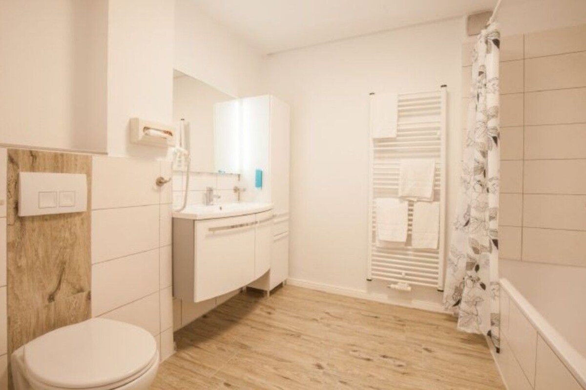 Een badkamer met toilet, wastafel, spiegel en douchegordijn.