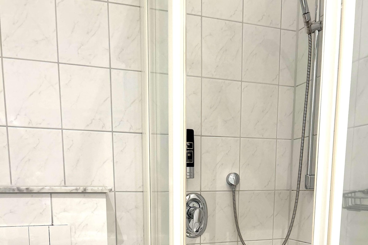 A modern bathroom with a glass-enclosed shower, a toilet, and a sink.