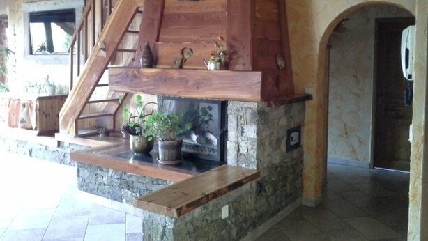 A wooden staircase with a stone fireplace below. There are potted plants on the lower landing.