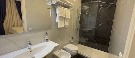 Un baño moderno con un espejo grande, un lavamanos, un bidé y una cabina de ducha.