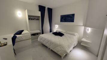 Een moderne slaapkamer met een groot bed, nachtkastjes, een kledingkast en een nachttafeltje.