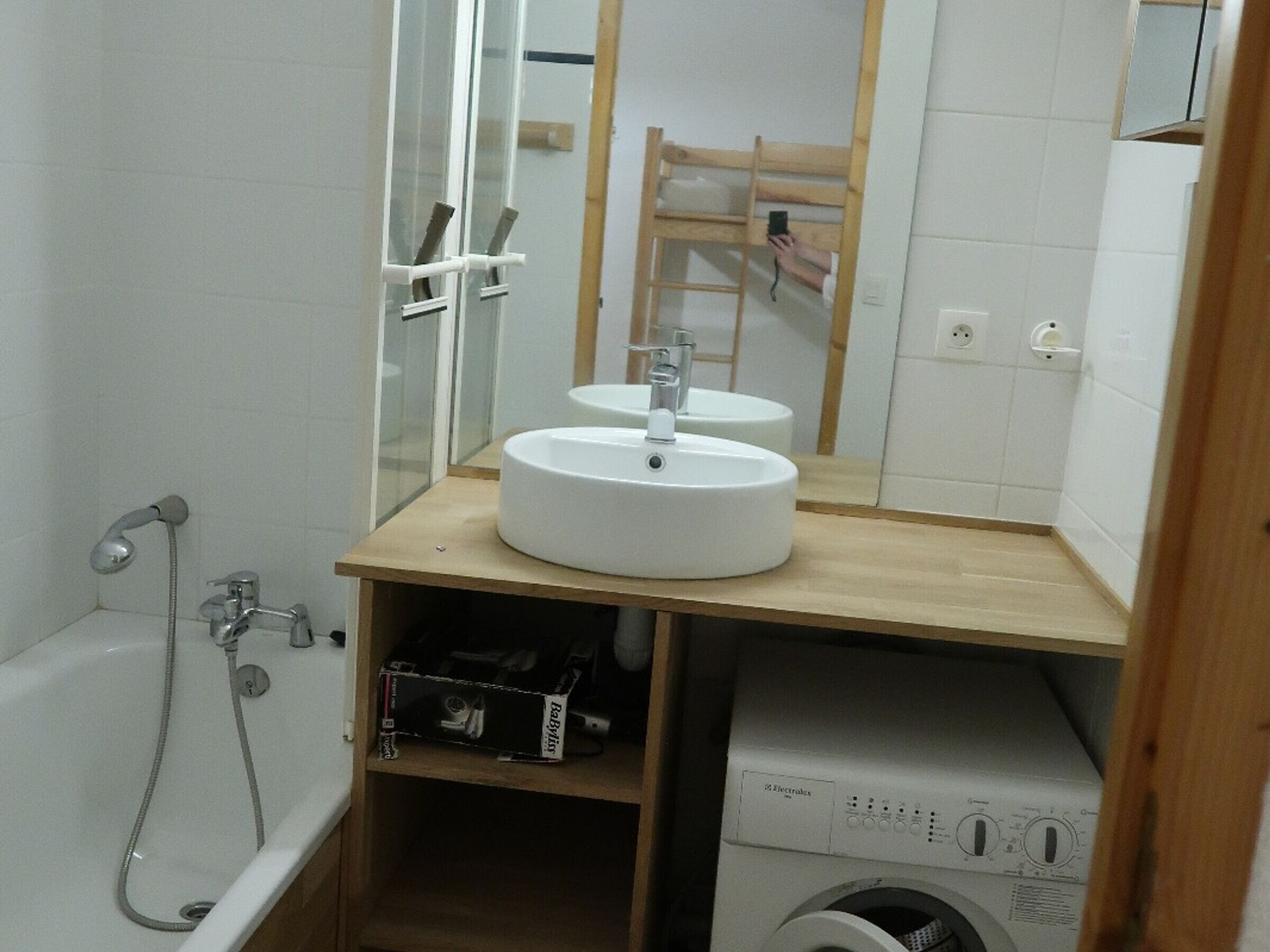 Un baño con bañera, dos lavamanos, un espejo y una lavadora.