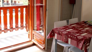 A room with a wooden balcony door, a table with a checkered tablecloth, and white chairs. - 2-room cabin apartment for 4 people, west facing with balcony and collective parking (Valloire)