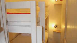 A narrow hallway with bunk beds, a door with a handle, and a light fixture on the wall. - 2-room cabin apartment for 4 people, west facing with balcony and collective parking (Valloire)