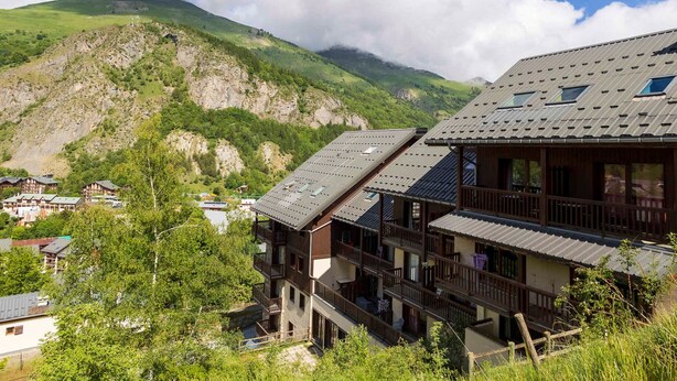 Un edificio de madera de varios pisos con balcones, frente a un paisaje montañoso.