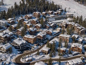 A snow-covered resort with multiple wooden buildings, a ski lift, and a winding road. - Ski-in apartment with spa in Courchevel 1850 (Courchevel 1850)