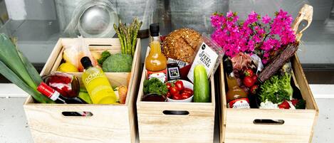 Three wooden crates filled with various groceries and flowers.