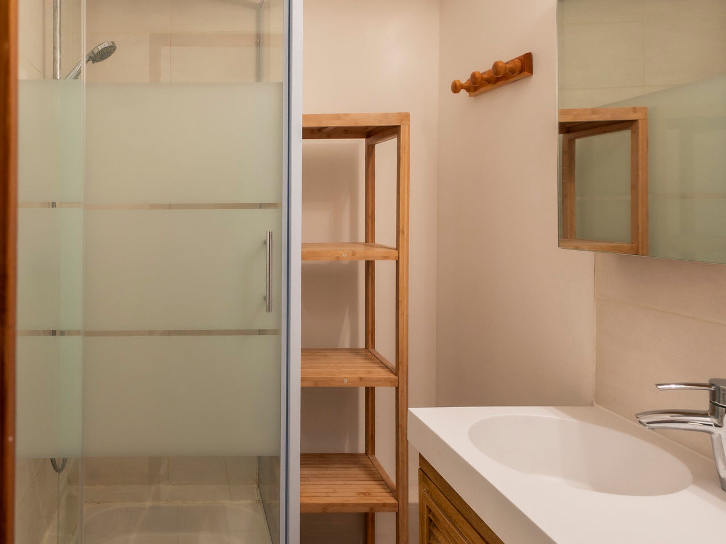 Une salle de bain avec une douche à parois de verre, un meuble-lavabo en bois et un miroir.