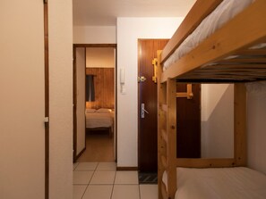 Una habitación con una litera, una puerta que da a otra estancia y un teléfono fijo en la pared.