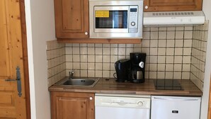A compact kitchen with a microwave, coffee maker, and dishwasher.