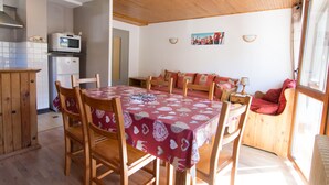 A cozy room with a wooden ceiling, a dining table with chairs, a sofa, and a kitchen area with a microwave and refrigerator. - 2-room apartment for 6 people south-facing in Valloire (Valloire)