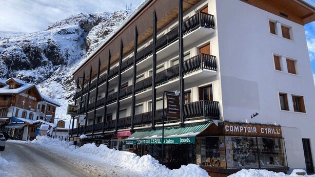 A multi-story hotel with balconies, a sign for 'Comptoir Cyrill', and a snowy mountain backdrop. - 2-room apartment for 6 people south-facing in Valloire (Valloire)