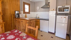 A compact kitchen with wooden cabinetry, a built-in dishwasher, a microwave, and a refrigerator. - 2-room apartment for 6 people south-facing in Valloire (Valloire)