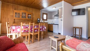 A cozy room with a wooden ceiling, a dining table with chairs, a sofa, a small table, and a kitchen area with cabinets and appliances. - 2-room apartment for 6 people south-facing in Valloire (Valloire)