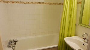 Une salle de bain avec une baignoire, un lavabo et un miroir.