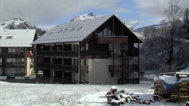 Un bâtiment à plusieurs étages, doté d’un toit en pente, qui ressemble probablement à un hôtel ou à un chalet, situé dans une région montagneuse enneigée.