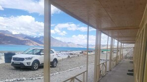 Un espacio al aire libre cubierto con un sendero de grava, columnas de madera y vistas a un cuerpo de agua y montañas.