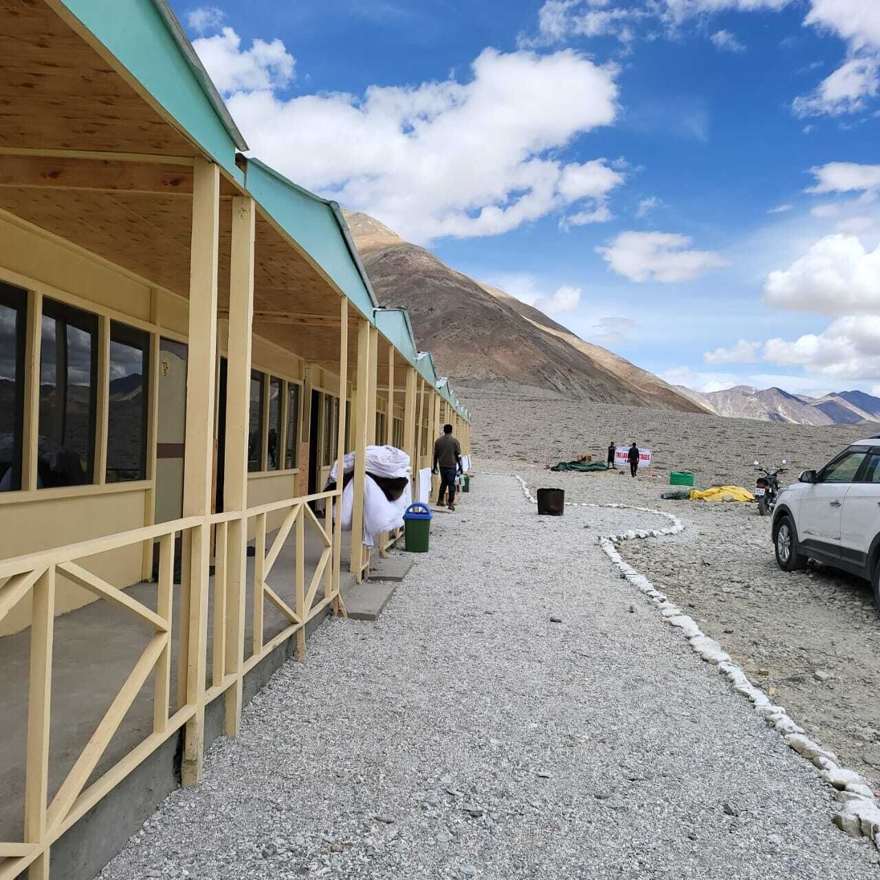 A building with a wooden exterior and a gravel ground, with a mountain in the background.