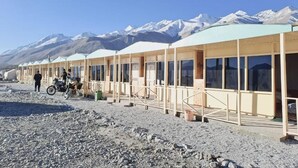 Una hilera de edificios sencillos de un solo piso con ventanales grandes, probablemente un hotel o albergue, con montañas nevadas al fondo.