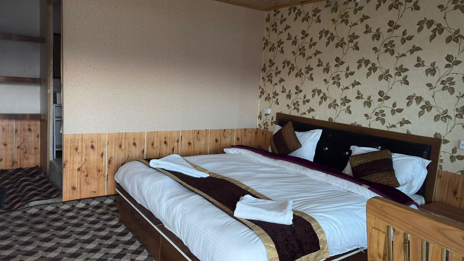 A room with a wooden bed, a checkered floor, and a floral wallpaper.