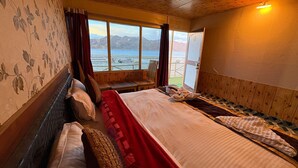 Una habitación con una cama, un ventanal con vistas a montañas y un techo de madera.