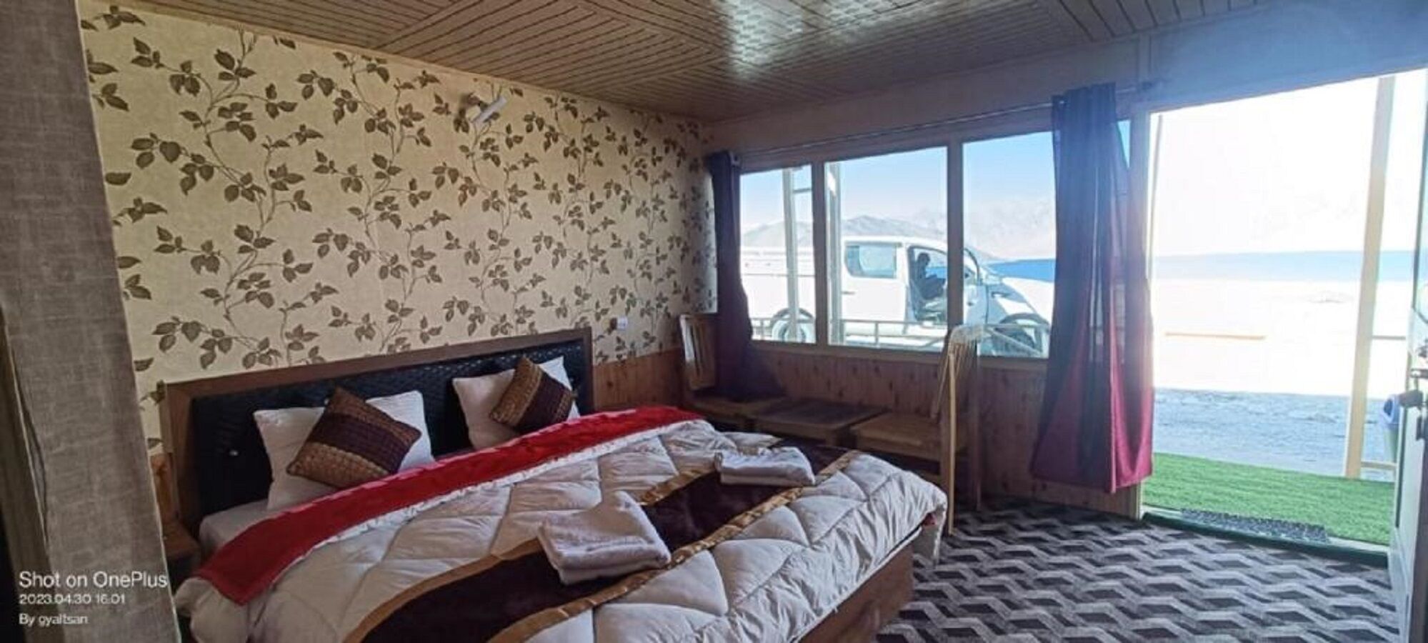 Ein Schlafzimmer mit einem Bett, einem Fenster mit Meerblick und einem Sessel am Fenster.
