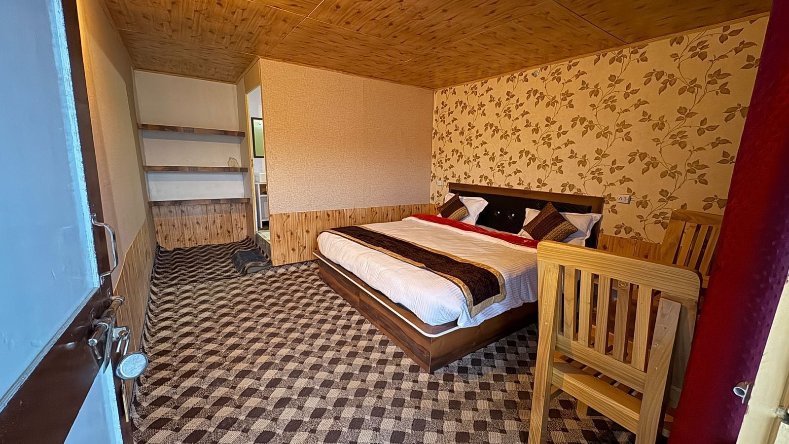 A bedroom with a bed, a chair, a wardrobe, and a patterned floor.
