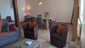 A living room with a sofa, two armchairs, a coffee table, and a dining area with a table and chairs.