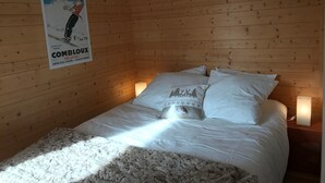 Une petite pièce en bois avec un lit, des oreillers et une affiche accrochée au mur.