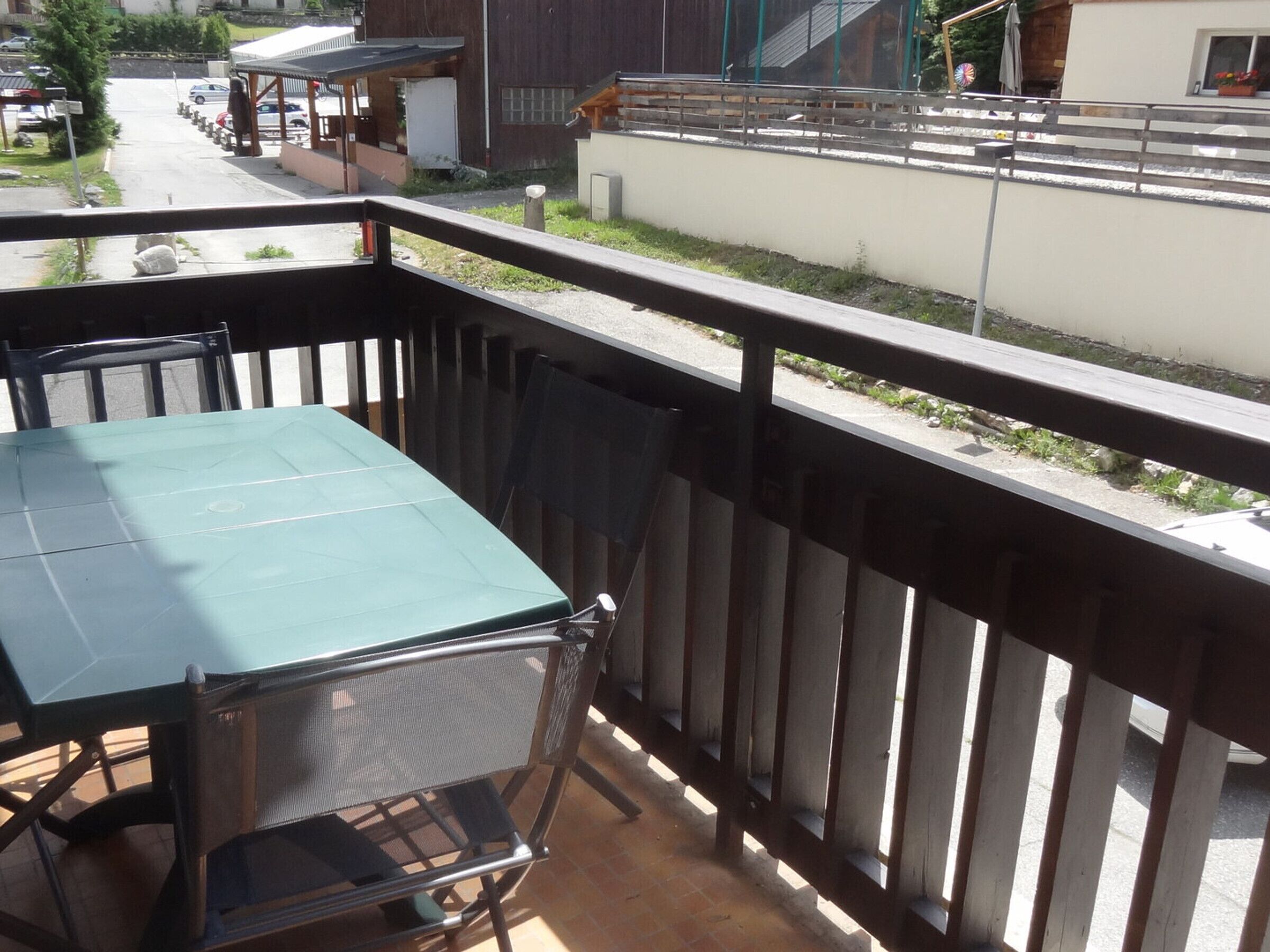 Ein Balkon mit Tisch und Stühlen, Blick auf die Straße und ein Gebäude im Hintergrund.