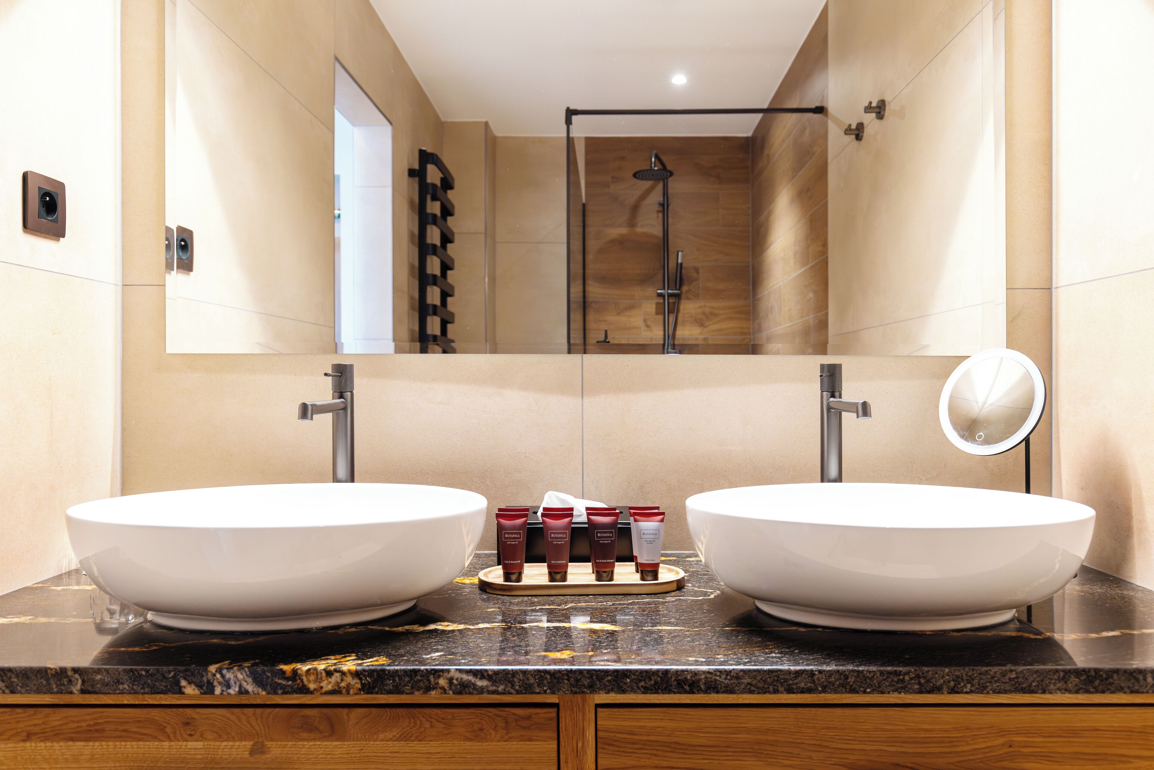 A modern bathroom with two large white sinks, a mirror, and a shower.