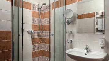 A bathroom with a glass-enclosed shower, a sink, and a mirror.